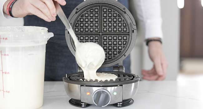 adding waffle batter to a waffle iron