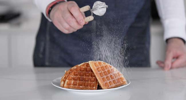 sprinkling powdered sugar onto waffles