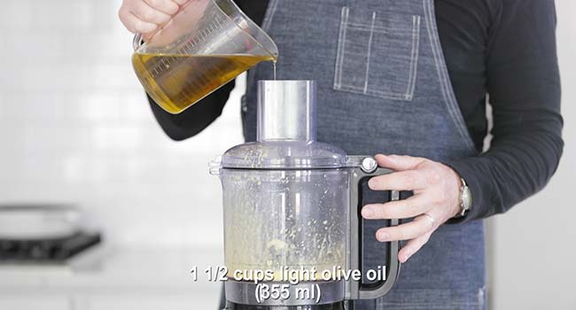 drizzling olive oil into a food processor