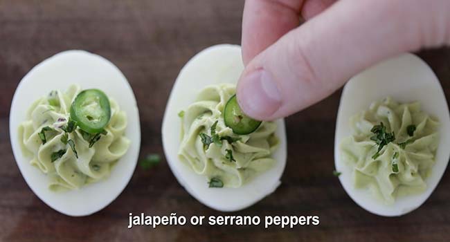 adding sliced jalapeños to avocado deviled eggs
