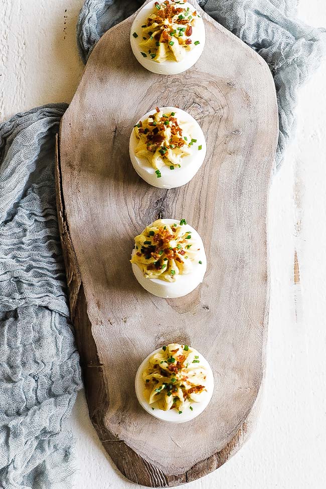 deviled eggs with bacon on a cutting board