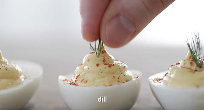 adding fresh dill to a deviled egg