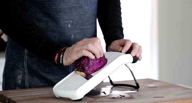 shredding red cabbage on a mandolin