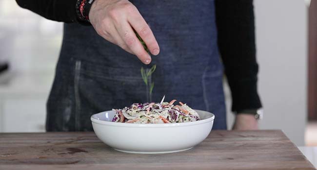 garnishing creamy coleslaw with sliced green onions