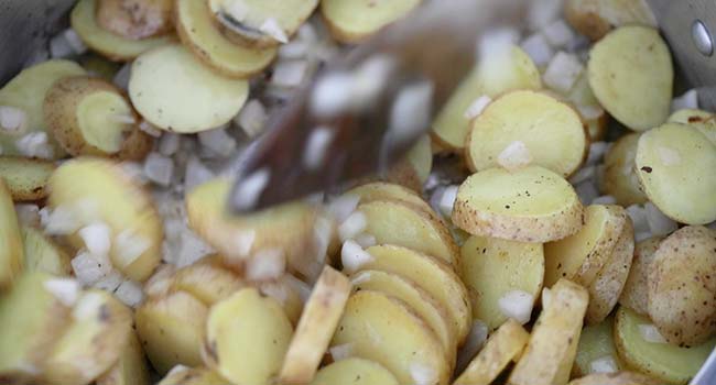 cooking sliced potatoes and onions in a pan