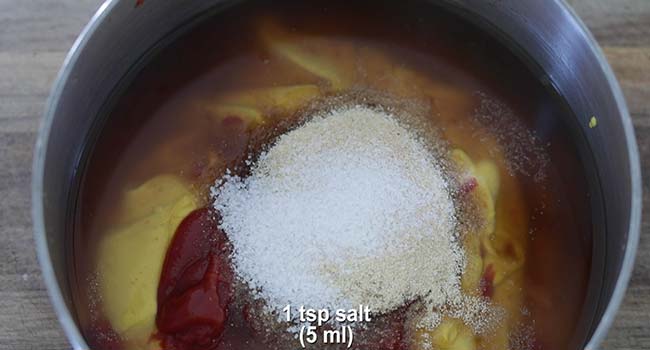 adding sugar to a pot of mustard bbq sauce