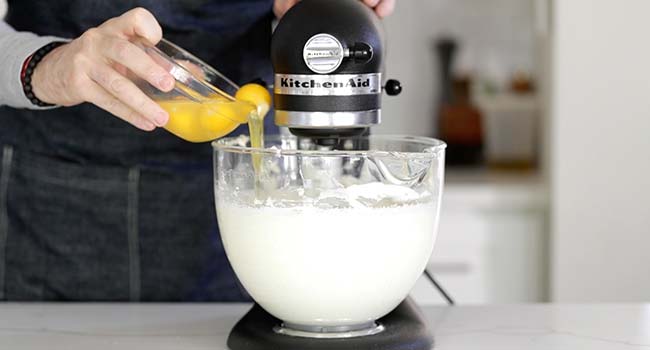 adding eggs to a stand mixer with pound cake batter