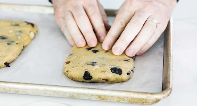 pressing down biscotti dough onto a cookie sheet tray