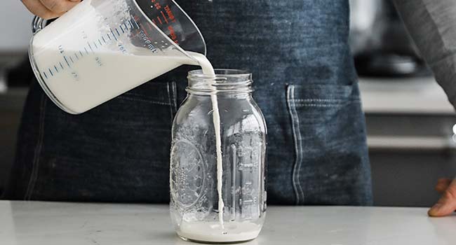 pouring heavy cream into a mason jar