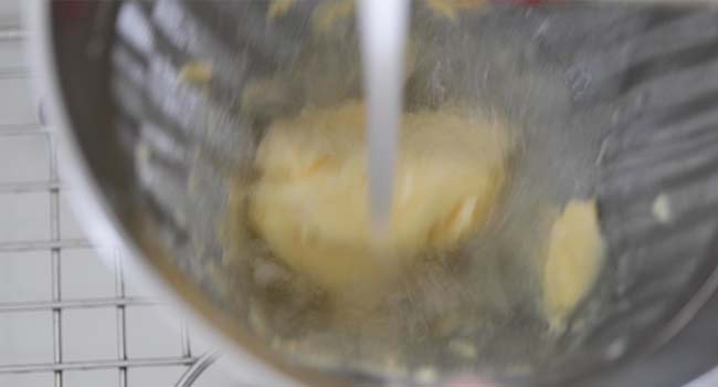 rinsing butter under cold water in a chinois