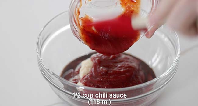 adding chili sauce to a bowl of ketchup