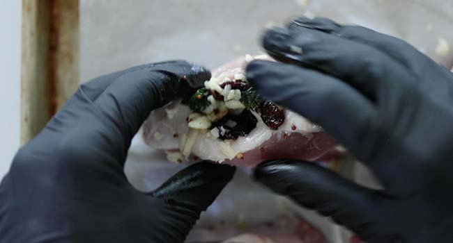 stuffing up a pork chop with dried cherry stuffing