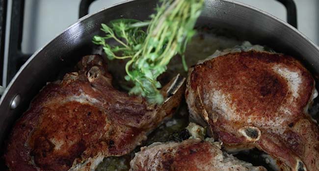 brushing cooked pork chops with fresh thyme