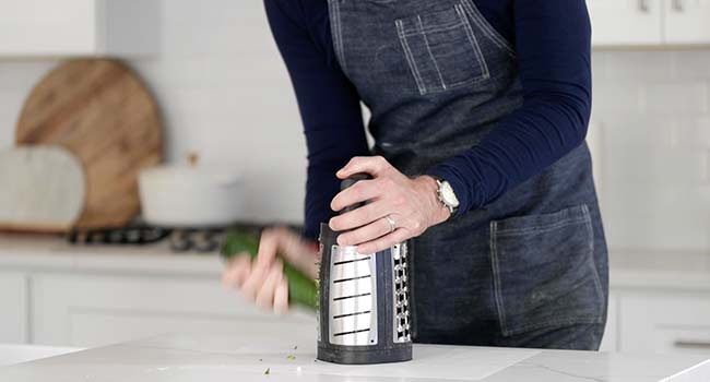 grating fresh zucchini on a grater