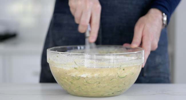 making a zucchini bread by mixing the batter