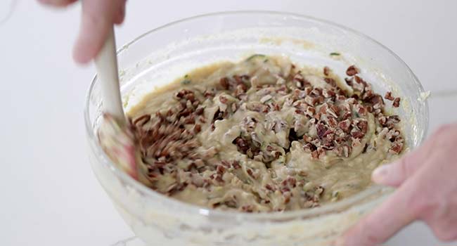 adding pecans to a batter in a bowl