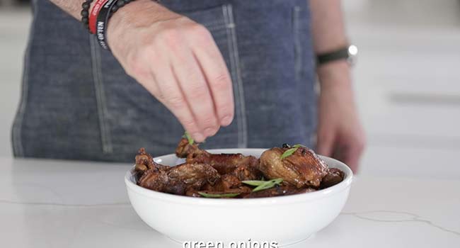 garnishing chicken with sliced green onions