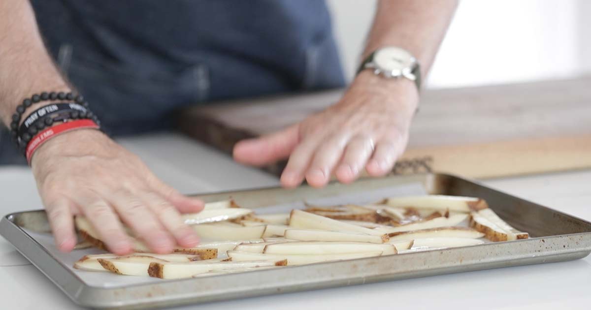 spreading out pommes frites on a cookie sheet tray