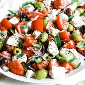 plate with sliced tomatoes cucumbers and olives