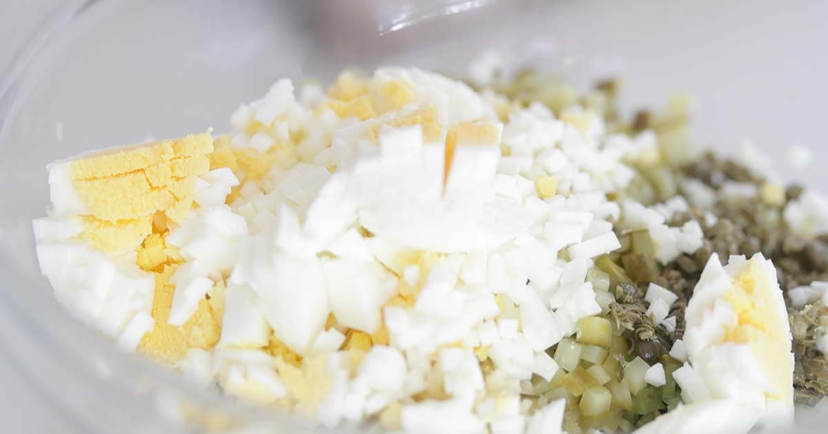 adding hard boiled eggs to a bowl with vegetables