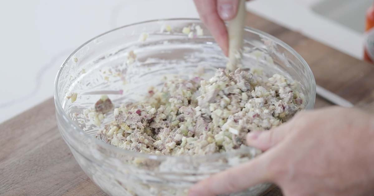 mixing together a tuna salad in a bowl