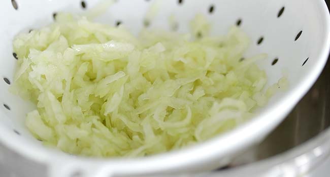 salting shredded cucumber in a strainer