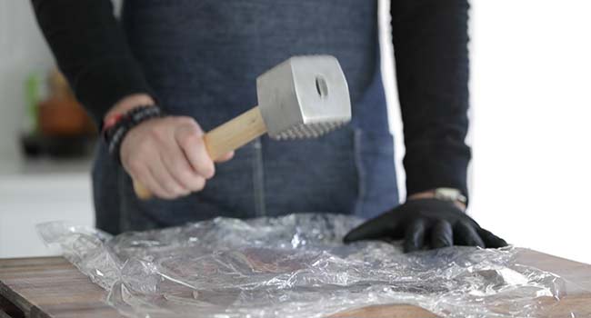 pounding chicken breasts using a mallet 