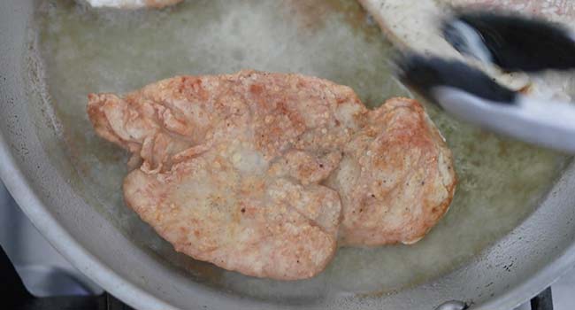 frying a chicken breast in a pan of oil