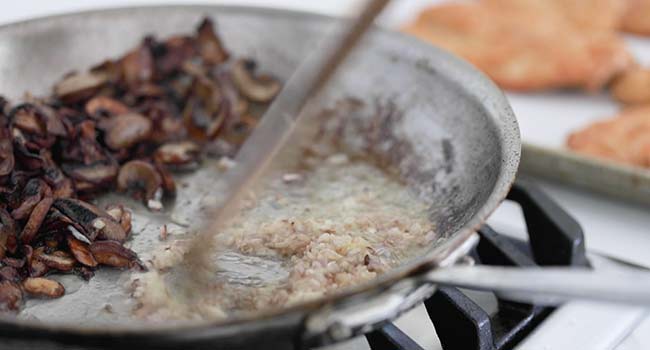 cooking shallots and garlic with mushrooms in a pan