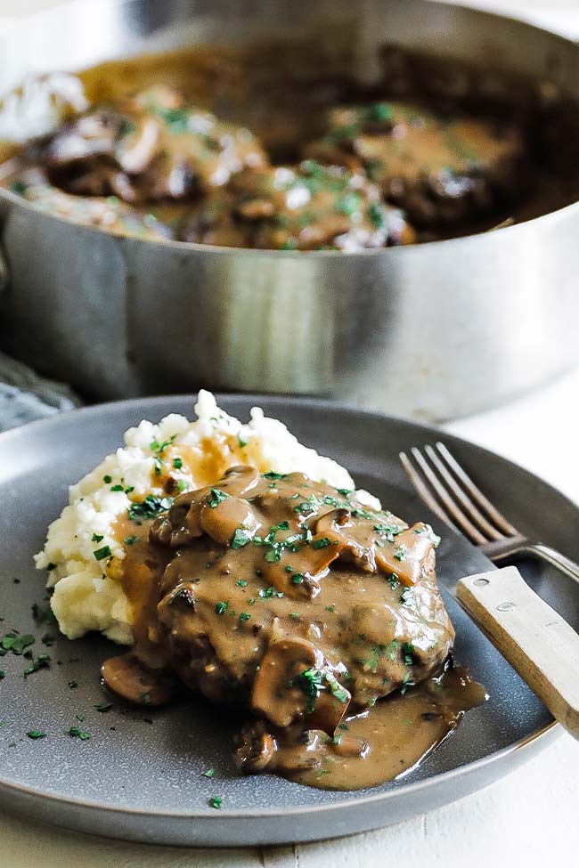 salisbury steak with mushrooms and gravy on mashed potatoes