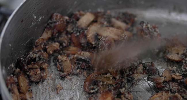 mixing cooked mushrooms with garlic