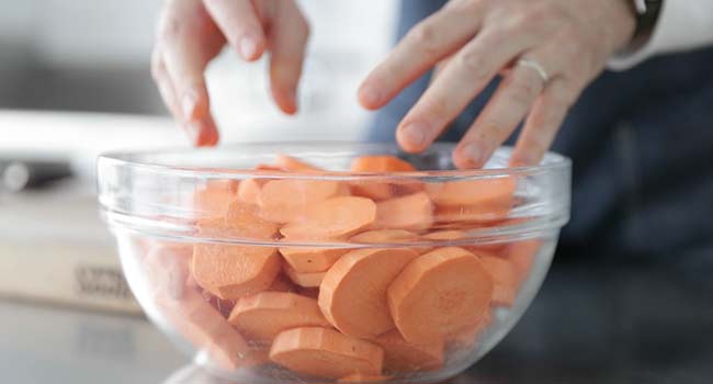 adding sliced sweet potatoes to a bowl