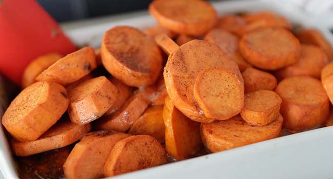 removing foil from a casserole dish of candied yams