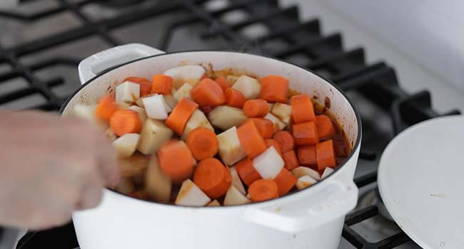 adding root vegetables to a pot