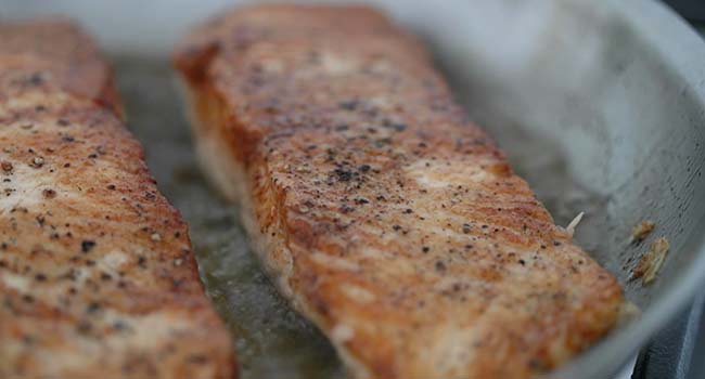 browning salmon in a pan with oil