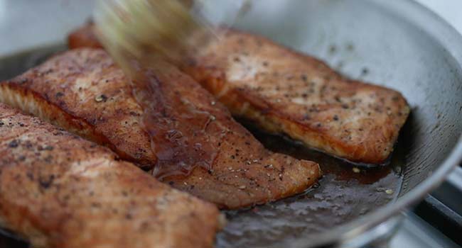 brushing salmon with a honey garlic sauce