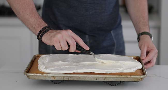 spreading cream cheese frosting over the top of pumpkin bars