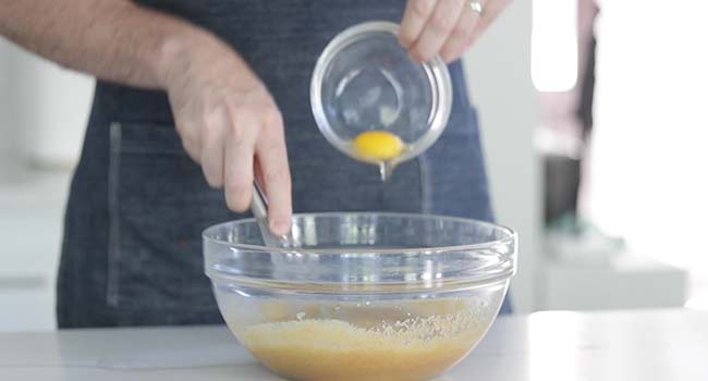 adding eggs to whisked sugar and oil