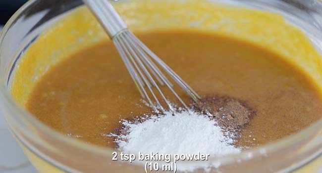 adding baking powder to a pumpkin bread batter