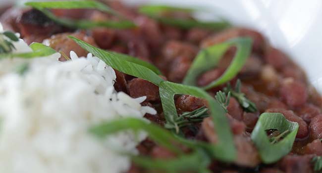 garnishing red beans and rice with sliced green onions and thyme