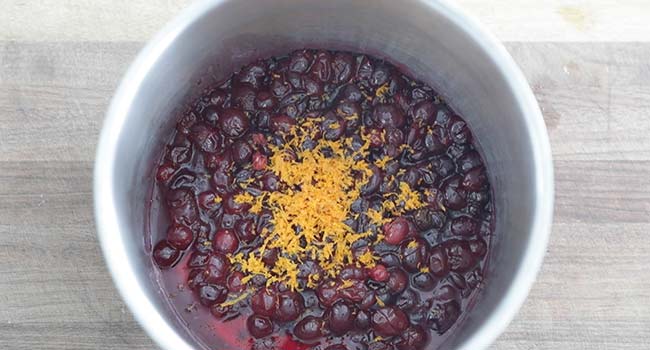 adding orange zest to cranberries