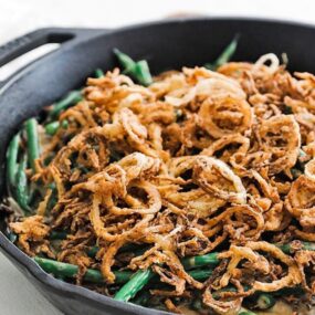 green beans with onion straws in a cast iron skillet