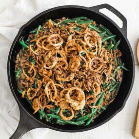 cast iron pan with green bean casserole on onion straws