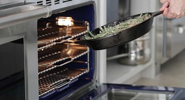 adding green bean casserole to an oven