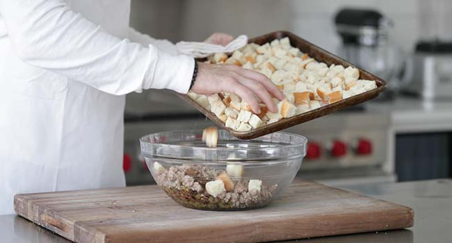 adding cubed bread to a bowl