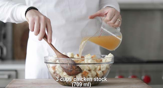 pouring chicken stock to a bowl with stuffing