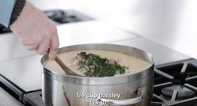 adding parsley and ham to a soup