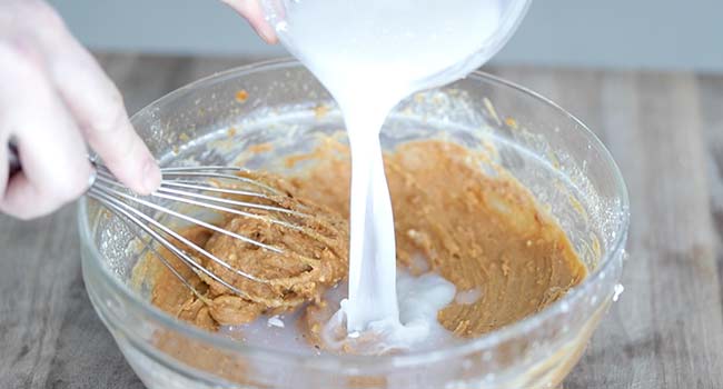 adding coconut milk to a peanut sauce