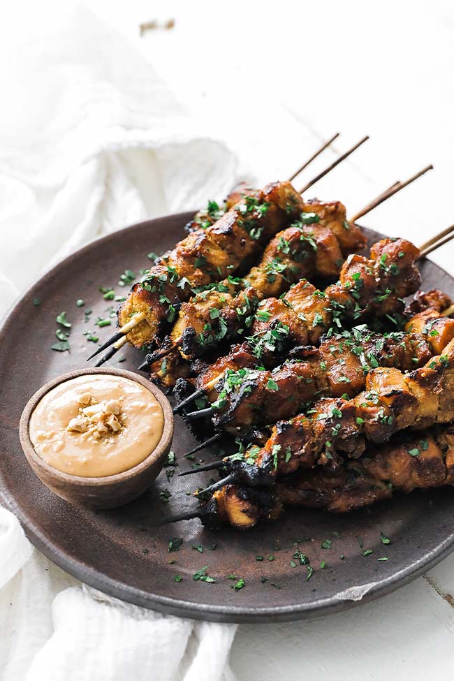 satay skewers on a plate with thai peanut sauce