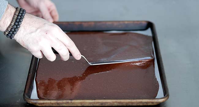 spreading a chocolate batter on a sheet tray